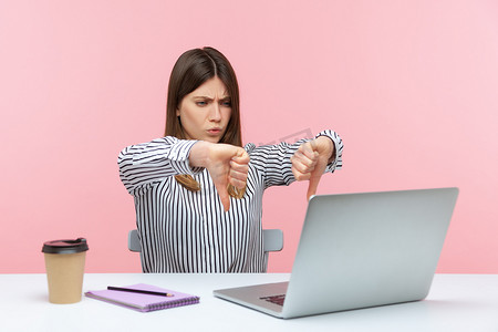 情绪化的年轻女性坐在粉红色背景的办公室里工作。