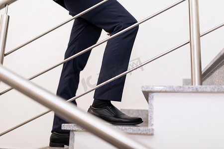 商人爬楼梯的腿特写、成功企业和职业发展的概念