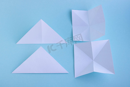 海报折纸摄影照片_第 1 步。蓝色背景上手工制作的白色时尚几何多边形纸折纸鱼。
