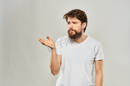 身穿白色 T 恤的男人用双手指着工作室不满的生活方式浅色背景