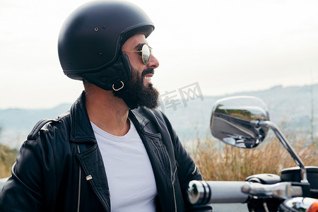 戴着头盔微笑着坐在他的摩托车上的骑自行车的人