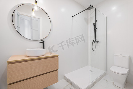 现代设计的白色浴室内部，配有淋浴区、卫生间、大理石地板、木制家具和圆镜