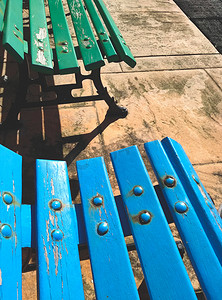 园区场景摄影照片_公园区蓝色和绿色彩绘木凳的特写