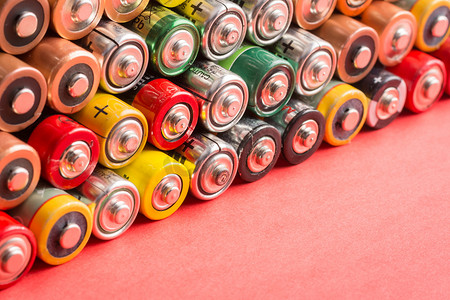 红色背景上堆放着不同制造商的电池、蓄电池