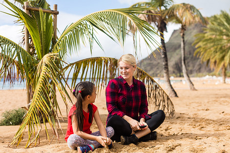 年轻的母亲和她的小女儿在海边的沙滩上
