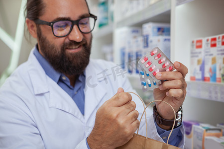 医生卖药摄影照片_快乐的药剂师在他的药店卖药