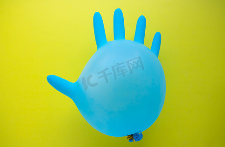 在黄色背景上以气球形式飞行的蓝色橡胶手术手套，带有空间副本。