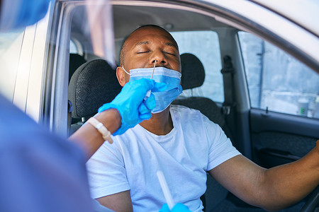 在医疗护士的协助下，一名驾车者在得来速加油站进行新冠病毒检测和筛查。