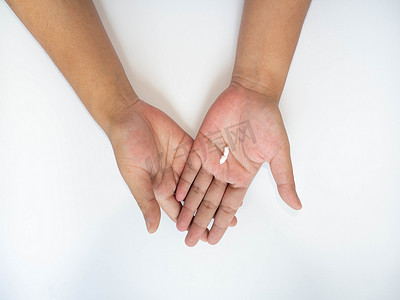 手上泡沫摄影照片_女人的手将霜挤到她的手上，为她的手涂抹保湿霜。