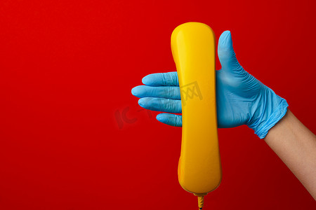 戴医用手套的女手拿着黄色电话扬声器