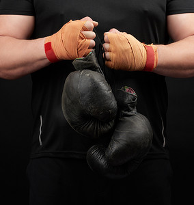 拳击黑摄影照片_一件黑色制服的肌肉运动员拿着非常古老的黑拳击