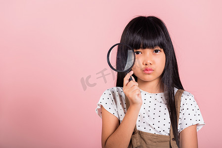 放大镜小孩摄影照片_10 岁的亚洲小孩通过放大镜看很有趣