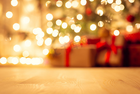 明亮温暖的灯光下，圣诞树的景色模糊，圣诞树下有美丽的礼物，重点是地板
