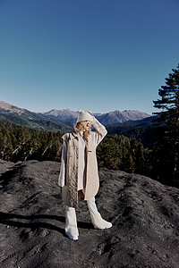穿着秋装的女人站在岩石蓝天的生活方式上
