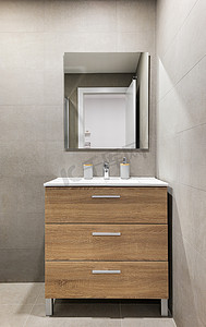 现代翻新浴室采用简约风格，配有灰色瓷砖墙壁、镜子和水槽下方的木制抽屉。