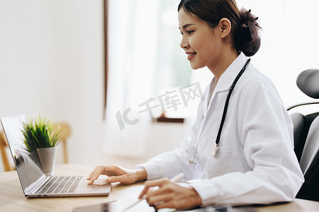 一位亚洲女医生使用电脑和平板电脑工作的肖像