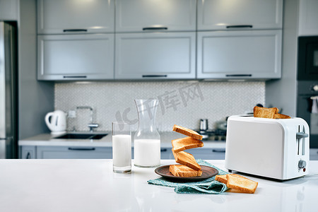 厨房模糊摄影照片_在模糊的背景下，早餐桌供应烤面包、牛奶和蜂蜜
