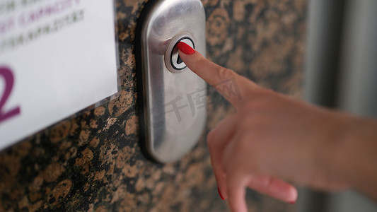 有红色美甲的女性手指按电梯按钮特写镜头