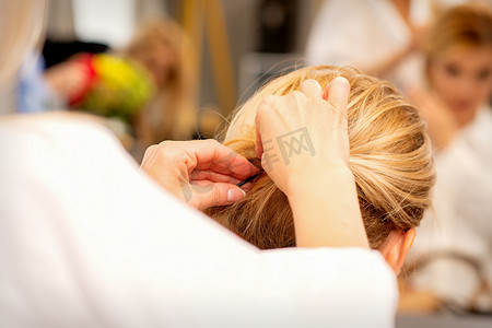 发型师的手在美容院为女性长发做专业发型设计。