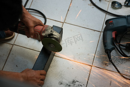 使用手册摄影照片_承包商正在使用电动打磨机对钢材焊接点进行装饰。