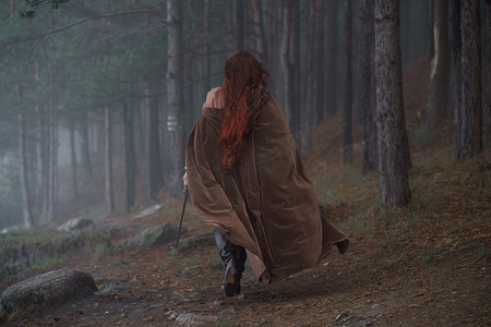 夏季森林中中世纪骑士盔甲的年轻红发女孩