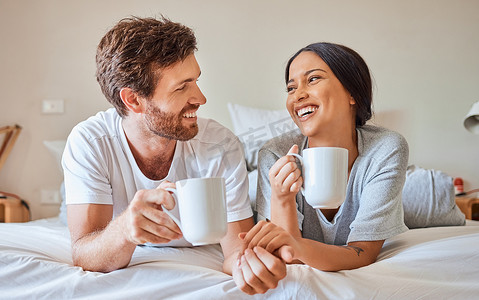 情侣咖啡，跨种族微笑，在家里的床上放松，为爱情婚姻微笑，在家里的卧室里进行有趣的交流。