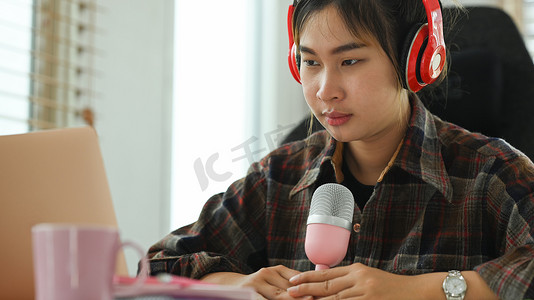 电台摄影照片_亚洲女电台主持人在家庭工作室录制播客。