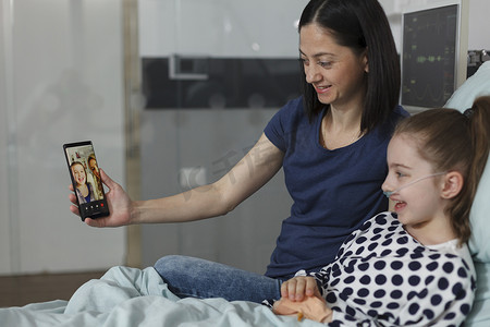 母亲和生病的女儿与最好的朋友通过智能手机虚拟视频通话