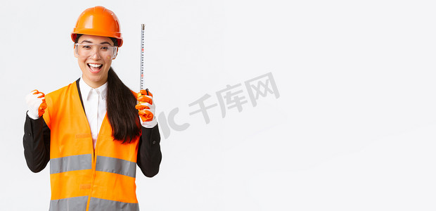 成功获奖的亚洲女建筑工程师完成工作，取得好成绩，拳头欢快地说是，拿着卷尺，建筑师做出正确的测量，欢欣鼓舞