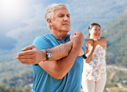 老人在户外锻炼时伸展身体并深呼吸。