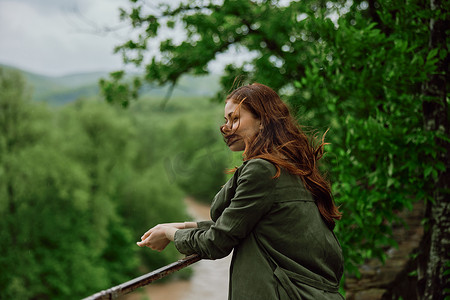 俯瞰山河摄影照片_一位红发随风飘扬的美丽女子站在公园里，俯瞰山河
