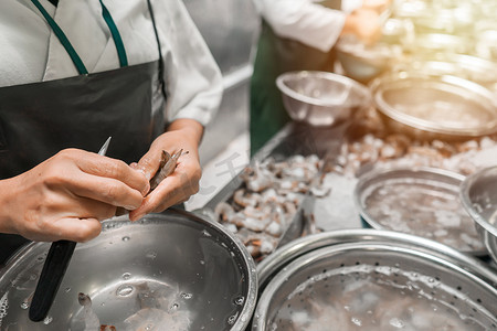 奇虾摄影照片_尼加拉瓜奇南德加一家食品厂里，一名无法辨认的拉丁裔工人用刀清洗虾