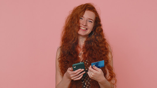 红发女孩在转账网上购物时使用信用卡和智能手机