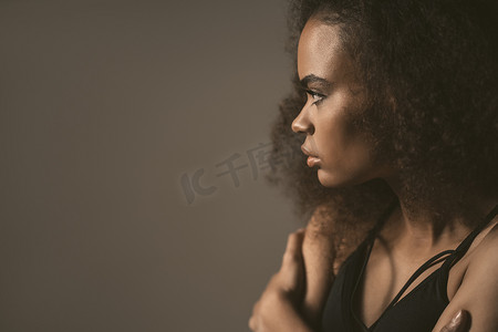 与或非摄影照片_悲伤或与男友分手后，非洲裔美国女孩站在灰色背景中孤立的黑色上衣。