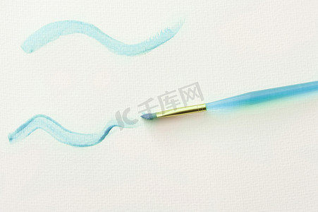 波浪天蓝色摄影照片_白纸上有蓝色波浪线的画笔