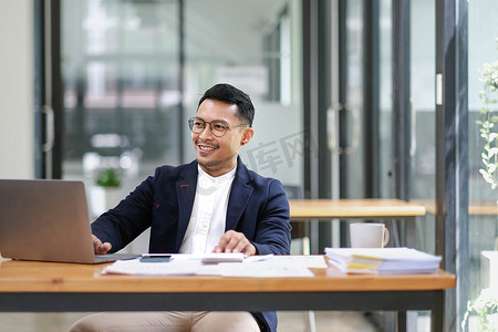 成功而专业的成年亚洲商人或穿着正式西装的男老板在办公桌上工作。