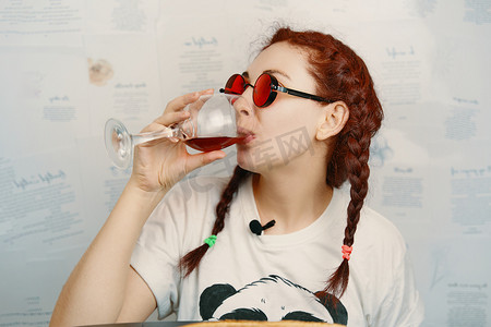 戴着圆形红色护目镜、扎着滑稽辫子的快乐女性喝着酒。