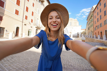 身穿蓝色连衣裙和帽子的微笑女孩在意大利马尔凯的安科纳自拍