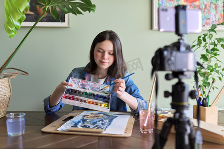教育频道摄影照片_艺术家女孩用水彩绘画并为她的频道博客制作视频