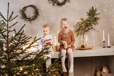 弟弟和妹妹在圣诞节前夕在为新年假期装饰的漂亮房子里玩耍。