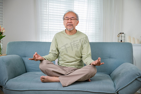 亚洲老人莲花坐闭眼练习瑜伽和冥想