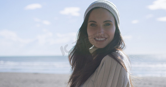 穿着秋装的女孩在海滩上微笑
