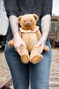 一个戴着眼镜和纹身的年轻白人女孩微笑着，一只棕色泰迪熊