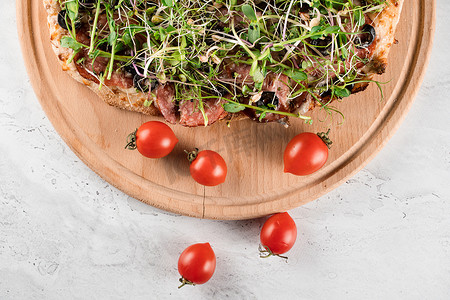微尔摄影照片_Pinsa romana 配意大利腊肠、奶酪、蘑菇，在白色背景的木板上装饰着微绿色植物。