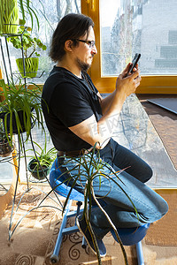 人体工程学摄影照片_一名男子坐在阳台上的符合人体工程学的矫形跪椅上打电话。