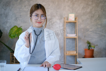 在私人诊所的办公室里，医生戴着眼镜微笑着展示听诊器工具。