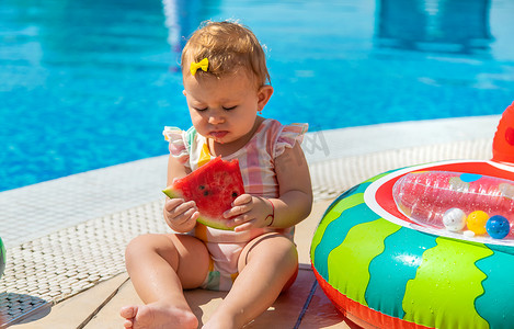 宝宝正在泳池边吃西瓜。