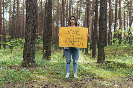 年轻女子在树林纠察队做志愿者，举着拯救森林的海报