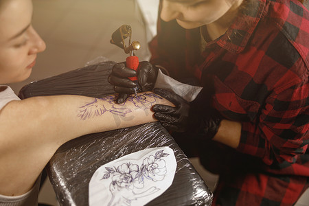 关闭纹身师手在客户手臂上绘制纹身