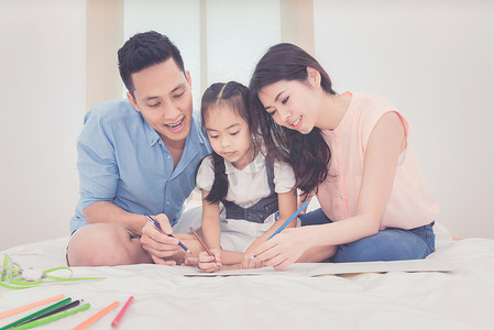 幸福的家庭在卧室里，亚洲父母教女儿在家学习